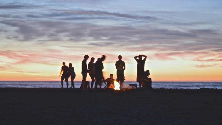 Junge Menschen mit Lagerfeuer am Strand