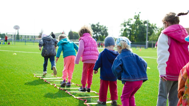 Bunt gekleidete Kinder in einer Reihe beim Sport 
