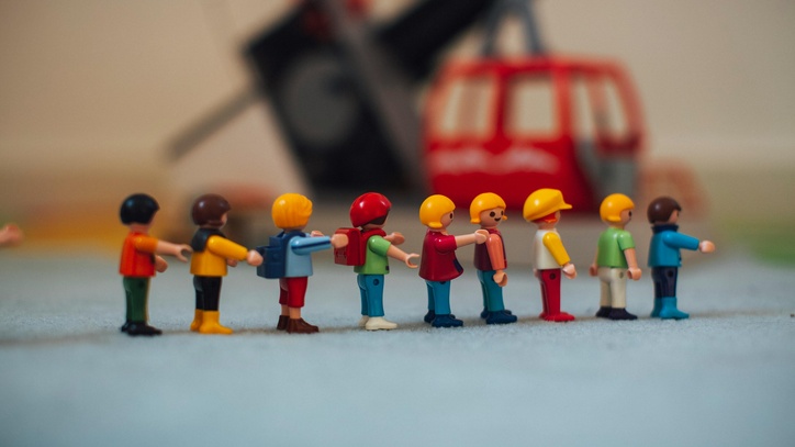 Eine Reihe von Playmobil-Kindern, die sich gegenseitig an den Schultern halten.