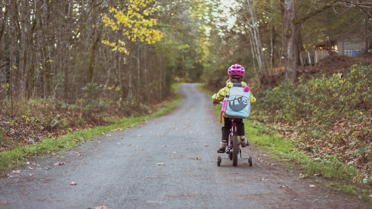 Ein Kind, das auf einem Fahrrad über einen Waldweg fährt.