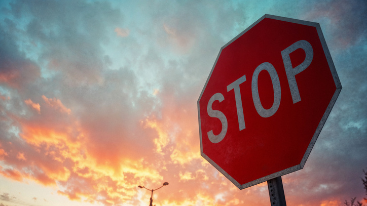 rotes 8-eckiges Stop-Schild vor blau orangenem Himmel