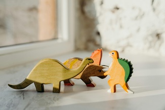 Drei Spielzeugdinosaurier, die so aussehen als würden sie streiten.