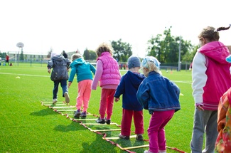Bunt gekleidete Kinder in einer Reihe beim Sport 