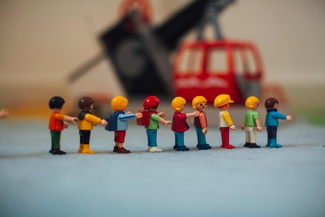 Eine Reihe von Playmobil-Kindern, die sich gegenseitig an den Schultern halten.