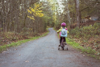 Ein Kind, das auf einem Fahrrad über einen Waldweg fährt.