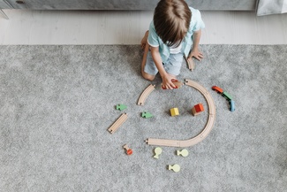 Ein Kind baut eine Strecke aus Spielzeuggleisen.