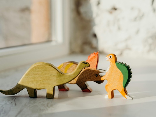 Drei Spielzeugdinosaurier, die so aussehen als würden sie streiten.