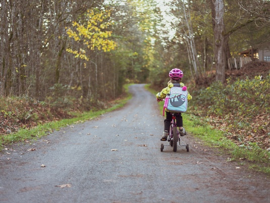 Ein Kind, das auf einem Fahrrad über einen Waldweg fährt.